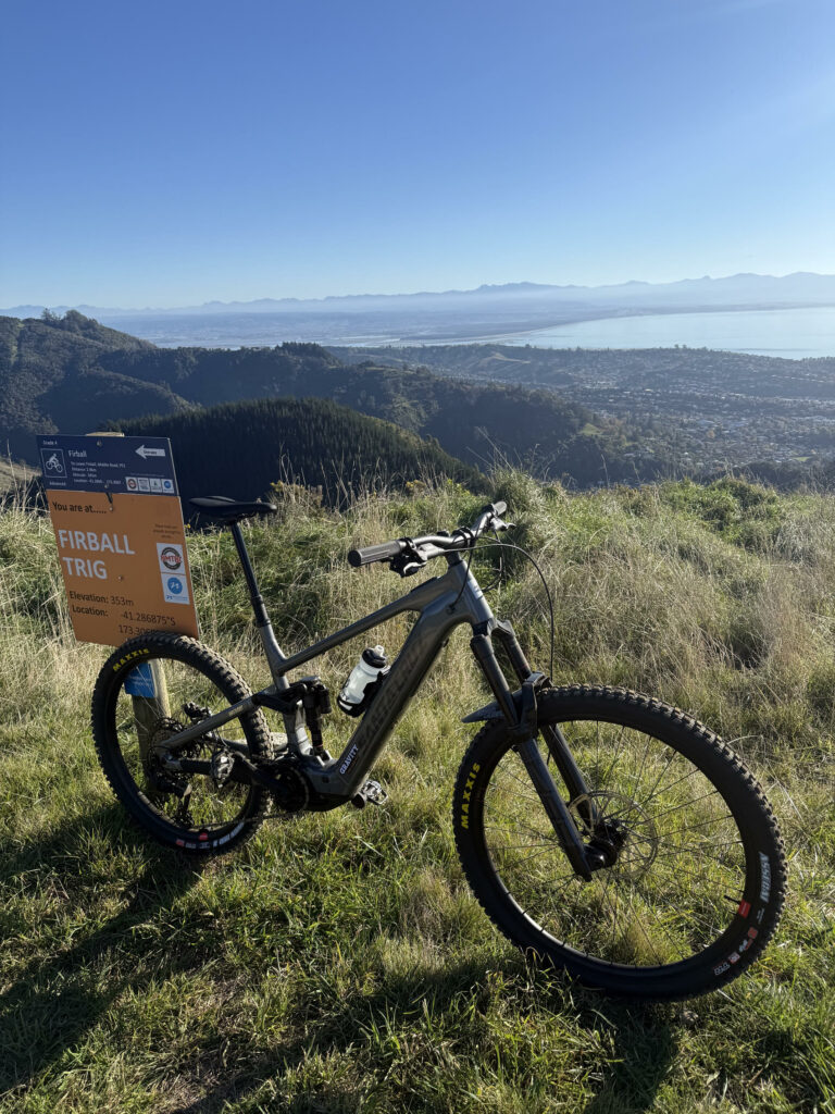 A 2026 Santa Cruz Vala Alloy full-sspensionelectric mountain bike leaning against asign in the Nelson Mountain Bike Park