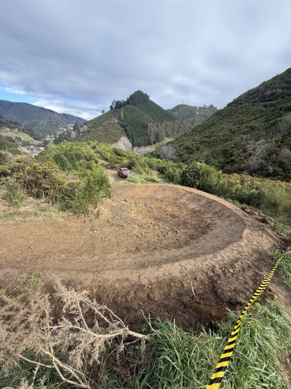 Mini excavator shaping new berm on flow trail