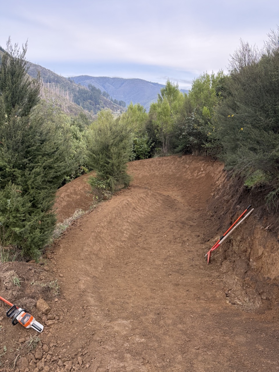 Large-scale trail construction on steep hillside with safety tape