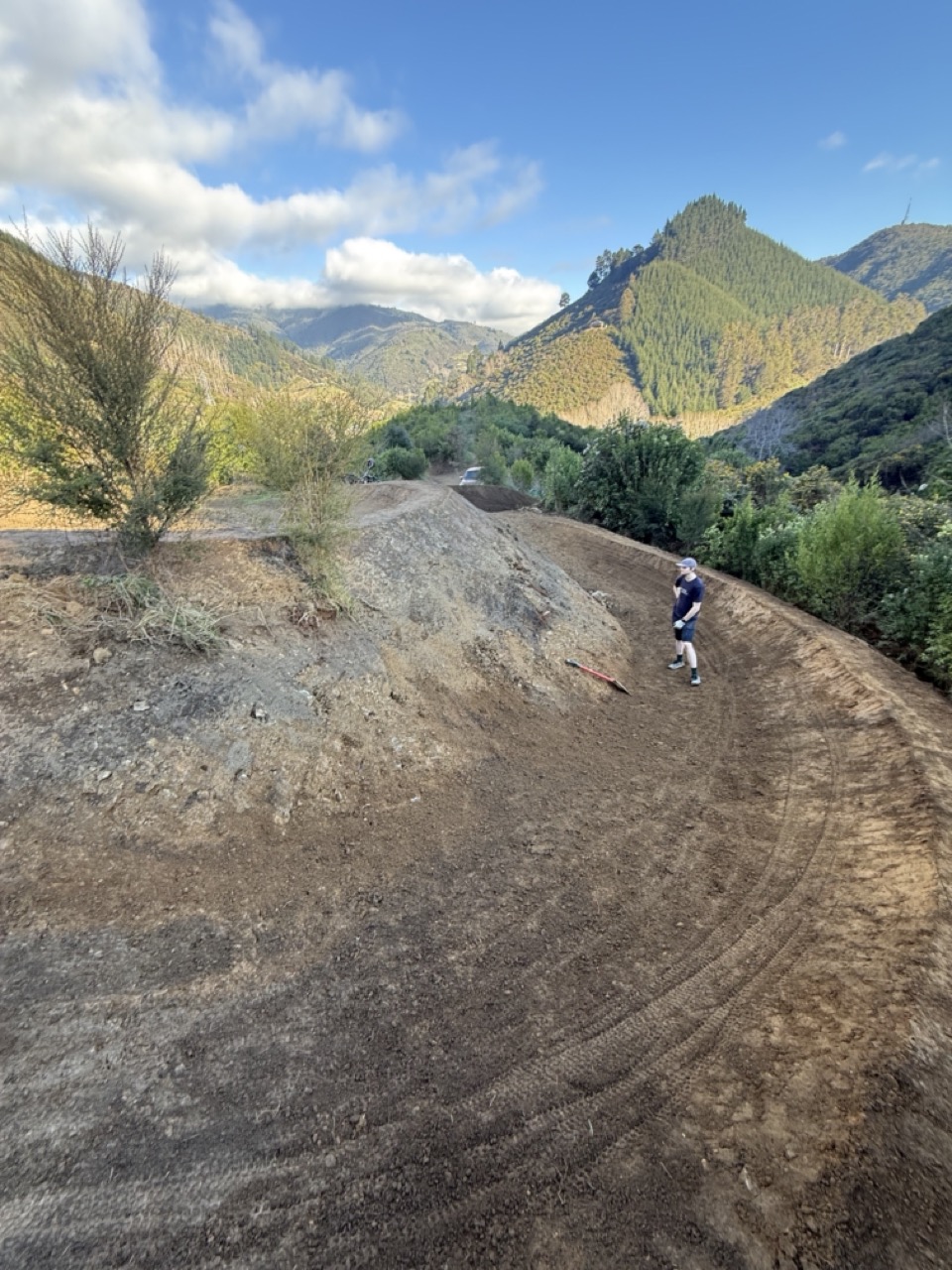 Trail builder inspecting hand-finished berm